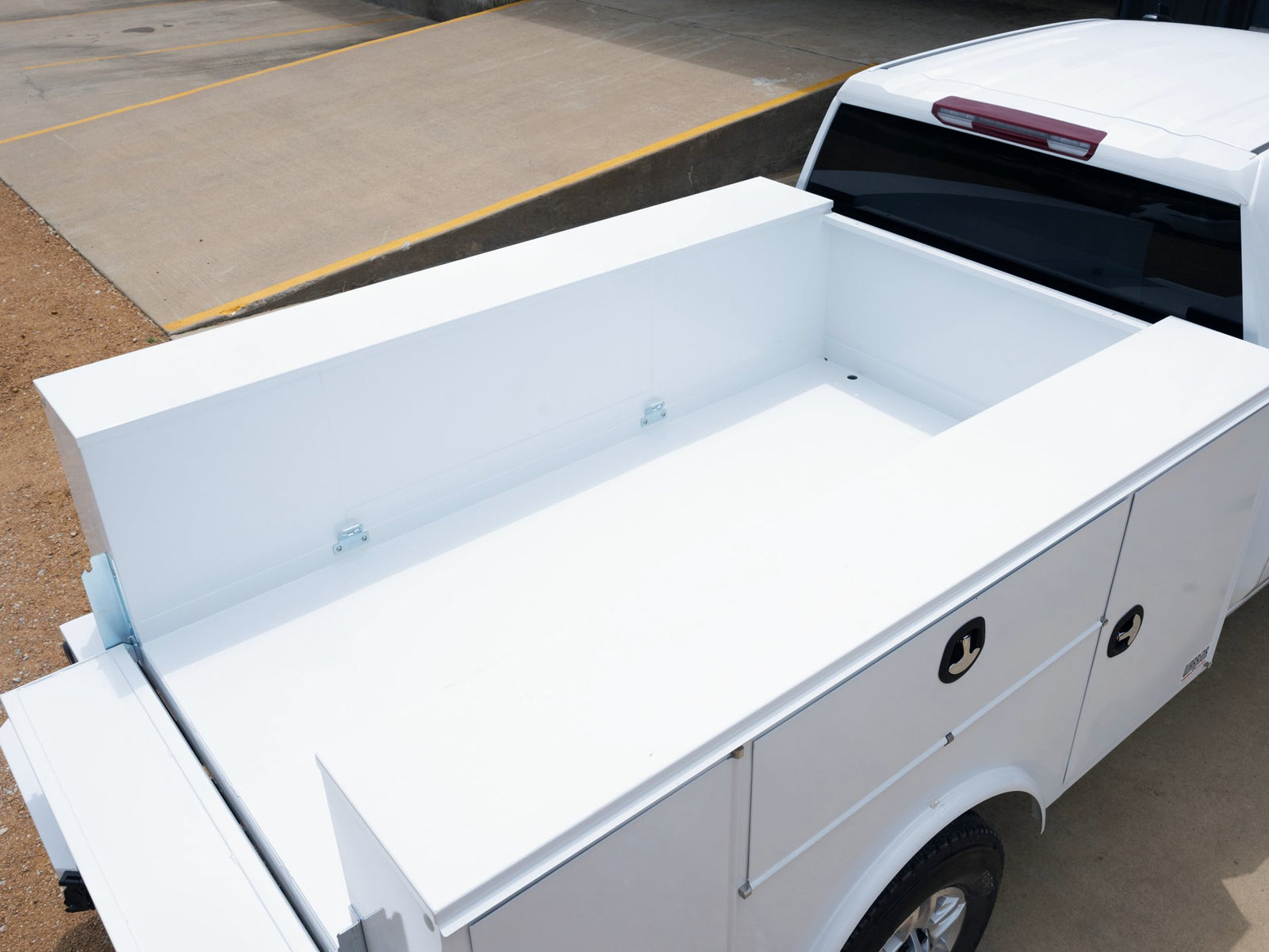 Overhead view of a white service body with an open bed and compartment tops on a white pickup